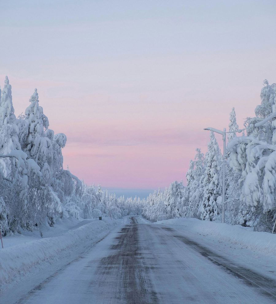 Snötäckt väg genom skog i skymning